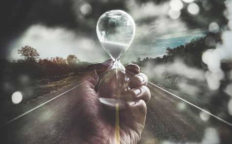 Hand holding hourglass on open road