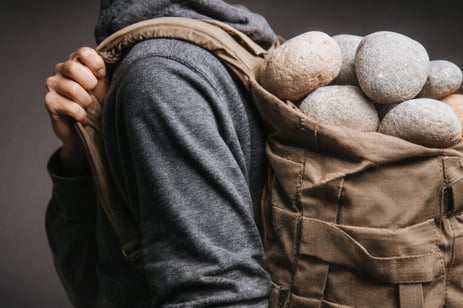 backpack filled with rocks carrying extra stress concept