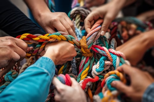 multiple hands untying a rope
