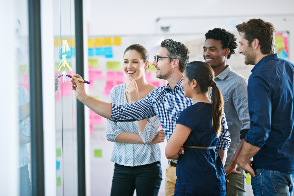 Creative Leadership Team brainstorming on glass board with sticky notes.